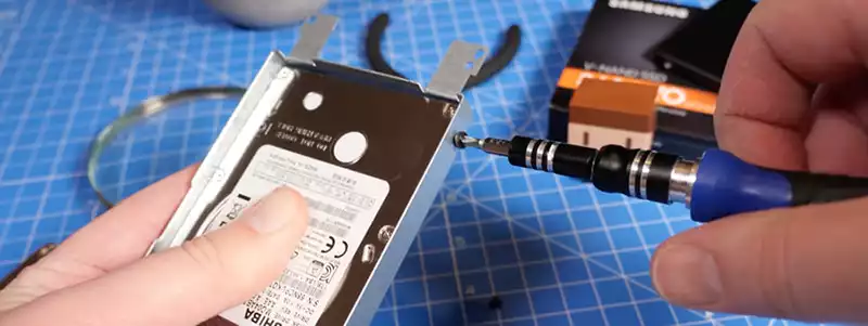 Detaching the Toshiba hard drive from its cradle.